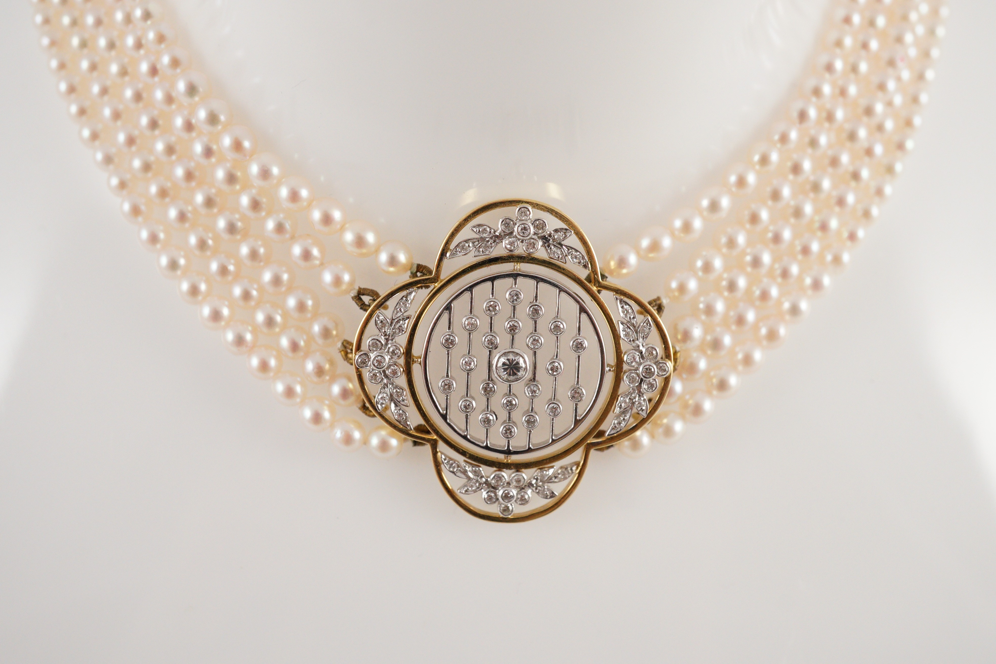 A quintuple strand seed pearl choker necklace, with pierced gold, platinum and diamond cluster set quatrefoil shaped clasp